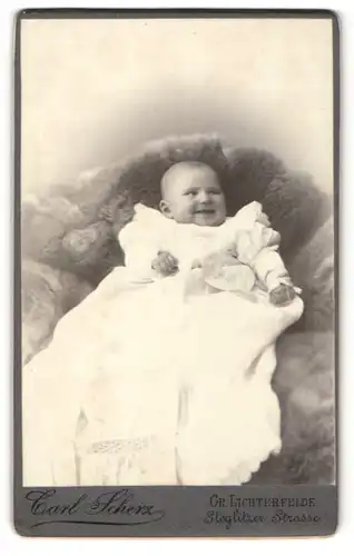 Fotografie Carl Scherz, Berlin-Lichterfelde, Portrait lachendes Baby auf einem Fell