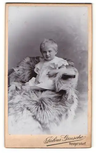 Fotografie Julius Grusche, Neugersdorf, Portrait blondes niedliches Kleinkind auf Fell sitzend