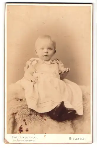 Fotografie Fritz Küken, Bielefeld, Portrait blondes niedliches Kleinkind im Schleifen-Kleidchen