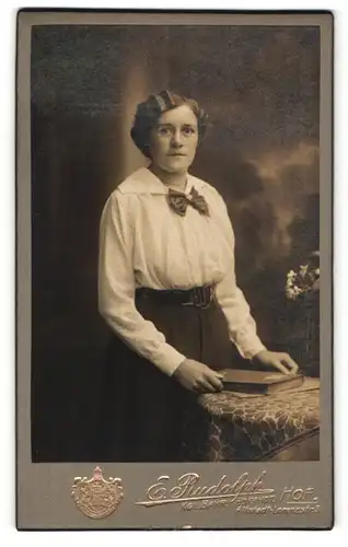 Fotografie E. Rudolph, Hof, Portrait brünette junge Frau mit Buch und Schleife am Kragen
