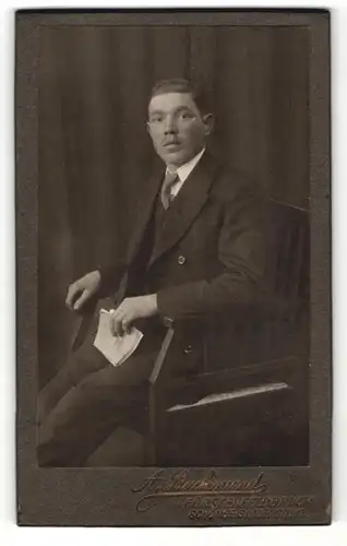 Fotografie A. Backmund, Fürstenfeldbruck, Portrait Herr im Anzug mit Buch auf Stuhl sitzend