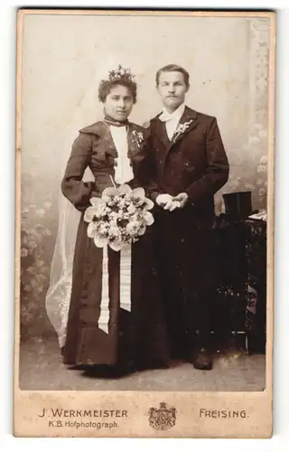 Fotografie J. Werkmeister, Freising, Portrait bürgerliches Paar in hübscher Hochzeitskleidung mit Schleier u. Blumen