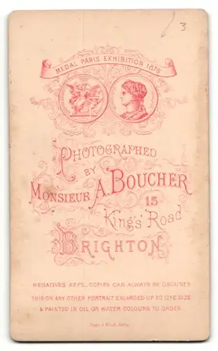 Fotografie Monsieur A. Boucher, Brighton, Baby im Kleidchen auf Pelzdecke sitzend