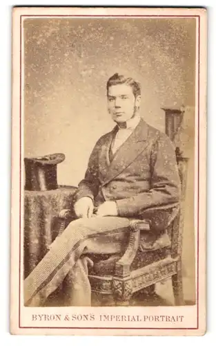 Fotografie Byron & Son`s, Nottingham, Mann mit Kotletten im Anzug auf Stuhl sitzend