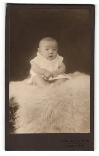 Fotografie Atelier Zinne, Bassum, Baby im Kleidchen auf Pelz sitzend