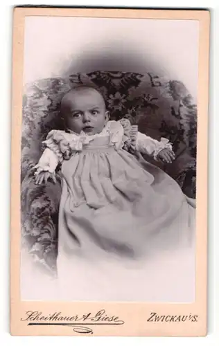 Fotografie Scheithauer & Giese, Zwickau, Baby im Kleidchen auf Sessel liegend