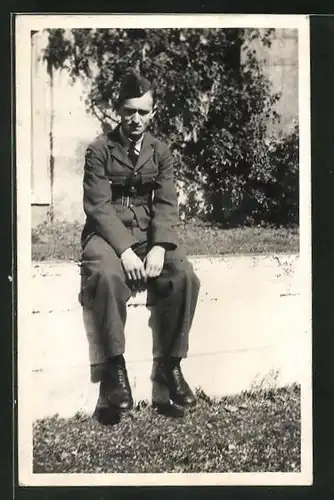 Foto-AK junger Soldat in britischer Uniform sitzt auf einer Mauer