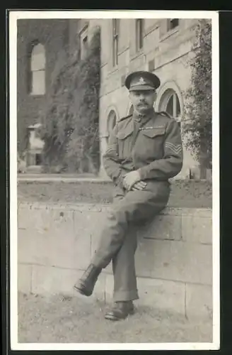 Foto-AK britischer Soldat in Uniform sitzt auf einer Mauer