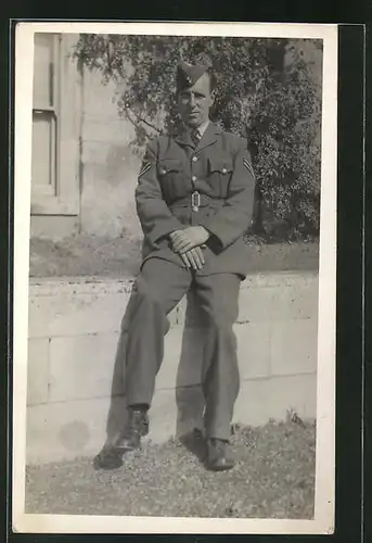 Foto-AK stattlicher Soldat in britischer Uniform auf einer Mauer sitzend