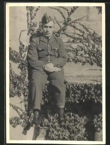 Foto-AK britischer junger Soldat in Uniform auf Mauer sitzend