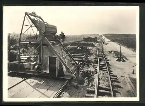 AK Strassenbau, grosse Baumaschine auf Gleisen beim Bau an einem Damm der Autobahn