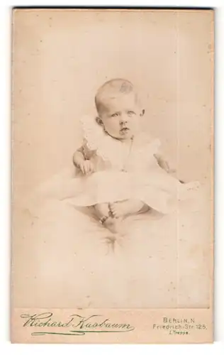 Fotografie Richard Kasbaum, Berlin, Baby in weissem Kleidchen sitzend