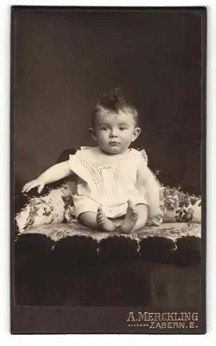 Fotografie A. Merckling, Zabern E., Kleiner Junge in weissen Klamotten auf Kissen