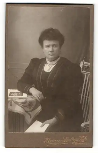 Fotografie Hermann Sontag, Zinnowitz, Frau im Kleid sitzend mit Zeitschrift in der Hand