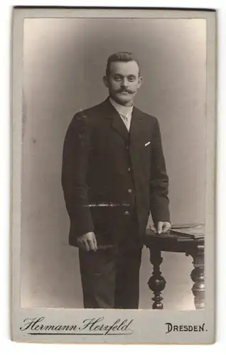 Fotografie Hermann Herzfeld, Dresden, Mann im Anzug mit Schnauzbart und Hand auf Tisch gestützt
