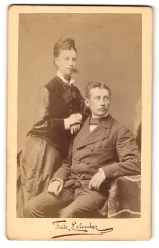 Fotografie Fritz Eilender, Cöln, Mann im Anzug sitzend und Frau im Kleid auf dessen Schulter gelehnt