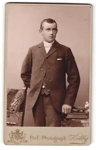 Fotografie Kolby, Zwickau, junger Mann im Anzug auf Buch gestützt und Blick nach oben