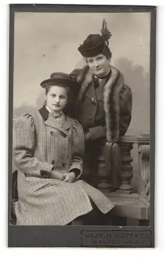 Fotografie Wilhelm Klopp & Co., Braunschweig, Frau im Mantel mit Hut und Pelzschal und Frau sitzend mit Hut