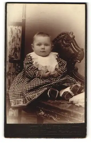 Fotografie M. Lüttgens, Görlitz, Baby im Kleidchen auf Bank sitzend