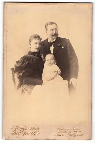 Fotografie Fritz Möller, Halle A/S., Herr mit Schnurrbart und Fliege neben Dame mit Baby