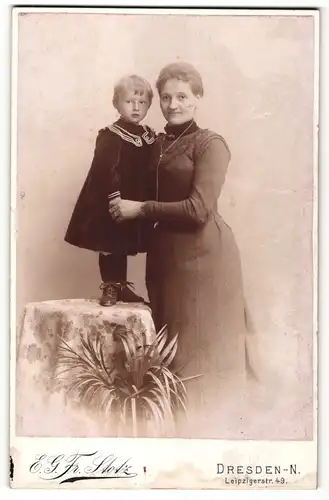 Fotografie E. G. Fr. Stotz, Dresden-N, Portrait Mutter im eleganten Kleid mit Kind auf Tisch stehend an der Hand
