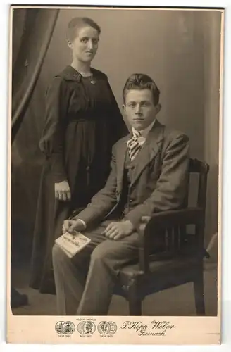 Fotografie P. Kopp-Weber, Reinach, Herr im Anzug mit Buch auf Stuhl sitzend u. Dame im schlichten Kleid