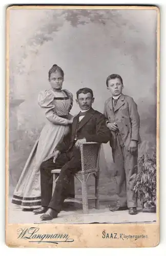 Fotografie W. Langmann, Saaz, Mann im Anzug sitzend und deneben Junge im Anzug und Mädchen im Kleid
