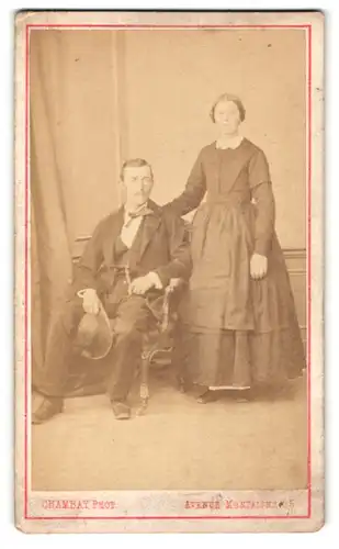 Fotografie Chambay, Paris, Mann im Anzug mit Hut sitzend und Frau im Kleid stehend