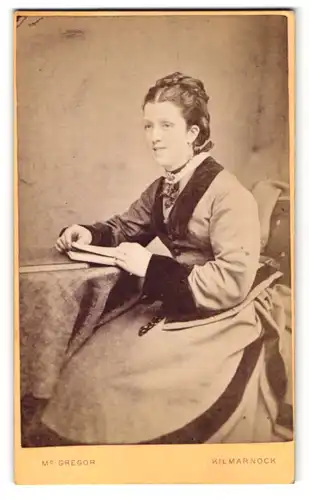 Fotografie M. Gregor, Kilmarnock, Frau im Kleid am Tisch sitzend mit Buch in den Händen