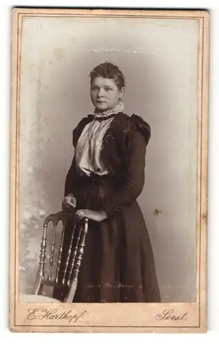 Fotografie E. Hartkopf, Soest, Portrait junge Dame im eleganten Kleid an Stuhl gelehnt