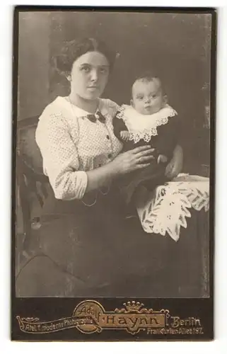 Fotografie Adolf Haynn, Berlin, Frau im Kleid sitzend mit Kind auf dem Arm