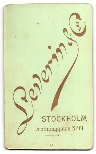Fotografie Leverin & Co., Stockholm, Kleinkind im Kleidchen auf Sessel sitzend