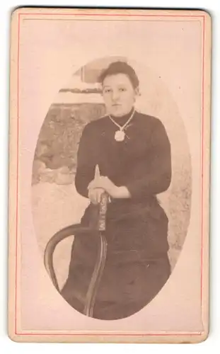 Fotografie unbekannter Fotograf und Ort, Frau im Kleid mit Halskette und breitem Amulett daran