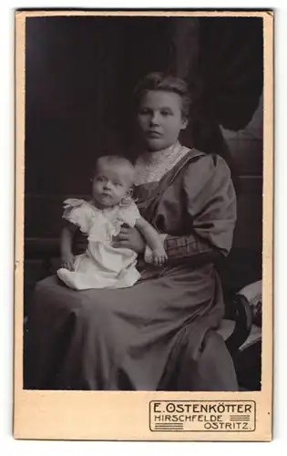 Fotografie E. Ostenkötter, Hirschfelde, Frau im Kleid sitzend mit Baby auf dem Schoss