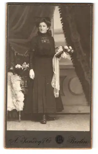 Fotografie A. Jandorf & Co., Berlin, Frau im Kleid stehend mit Blumenstrauss in der Hand