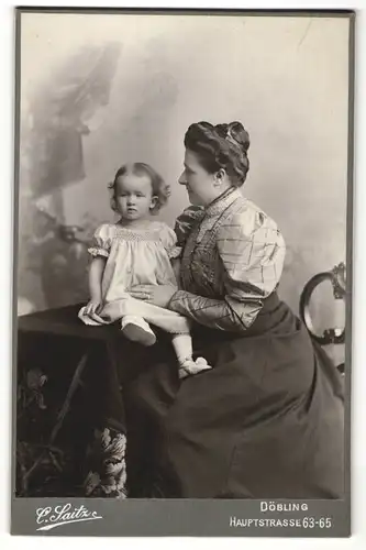Fotografie Carl Saitz, Wien-Döbling, Portrait bürgerliche Mutter am Tisch sitzend mit Tochter im Arm