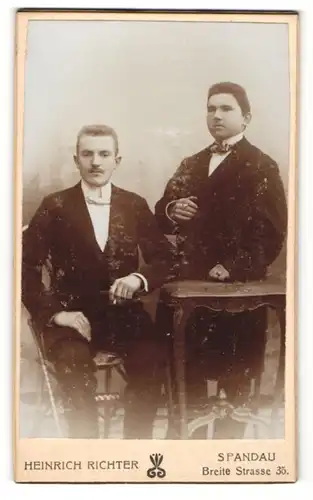 Fotografie Heinrich Richter, Berlin-Spandau, Portrait zwei charmante Herren in Anzügen mit Fliegen u. Zigaretten