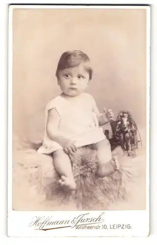 Fotografie Hoffmann & Jursch, Leipzig, Kleinkind im Kleidchen auf Pelz sitzend