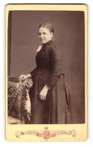 Fotografie Joseph Simpson, Tunstall, Frau im Kleid stehend mit breitem Unterkörper