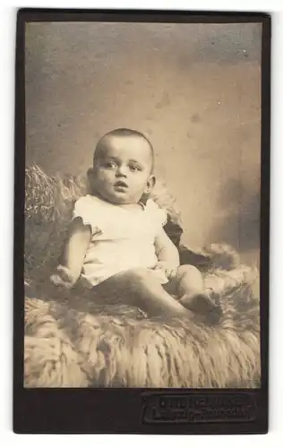 Fotografie Otto Reinicke, Leipzig-Paunsdorf, Baby im Kleidchen auf Pelz sitzend