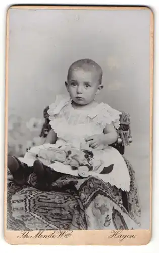 Fotografie Th. Mende Wwe, Hagen, Portrait Baby im weissen Kleid auf einem Stuhl posierend