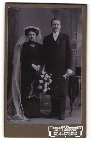 Fotografie Julius Grusche, Neugersdorf i/S., Mann im Anzug und Frau in dunklem Kleid mit Schleier und Brautstrauss