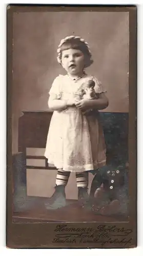 Fotografie Hermann Böbers, Berlin-Neukölln, Portrait kleines Mädchen im hübschen Kleid mit Puppe auf Bank stehend