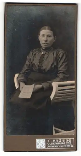 Fotografie C. Brüning, Oldenburg i / Gr., Portrait ältere Dame in hübscher Kleidung mit Heft auf Stuhl sitzend