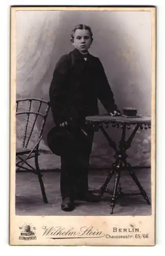 Fotografie Wilhelm Stein, Berlin, Portrait Bub in Anzug mit Hut