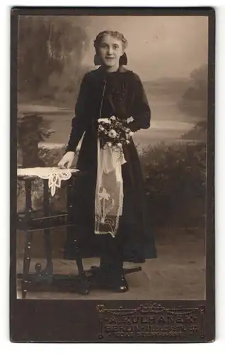 Fotografie A. Kulhanek, Berlin, Frau im Kleid stehend mit Blumenstrauss in der Hand