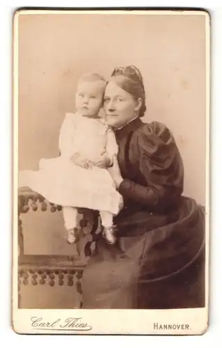 Fotografie Carl Thies, Hannover, Frau sitzend mit Kleinkind neben sich auf Tisch sitzend
