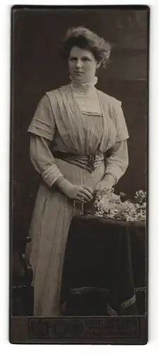Fotografie Wilh. Redeke, Hildesheim, Frau im Kleid stehend mit hochtopierten Haaren