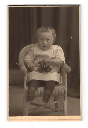 Fotografie unbekannter Fotograf und Ort, Portrait von einem Kind im Stuhl mit einem Rosenstrauss in der Hand