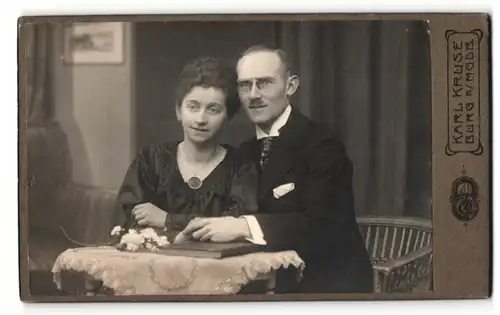 Fotografie Karl Kruse, Burg s/MGDB, Mann im Anzug mit Brille zusammen mit Frau im Kleid mit Halskette und Amulett